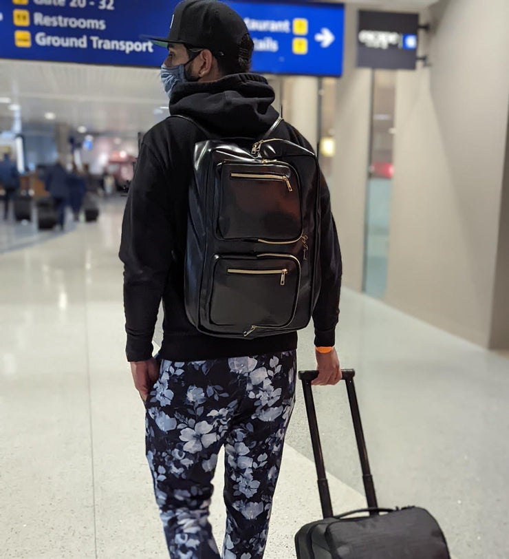 Backpack with multiple compartments Modern design travel backpack Man pulling suitcase and wearing backpack Man wearing backpack at airport Traveler with black luxury backpack Young professional traveling with backpack
